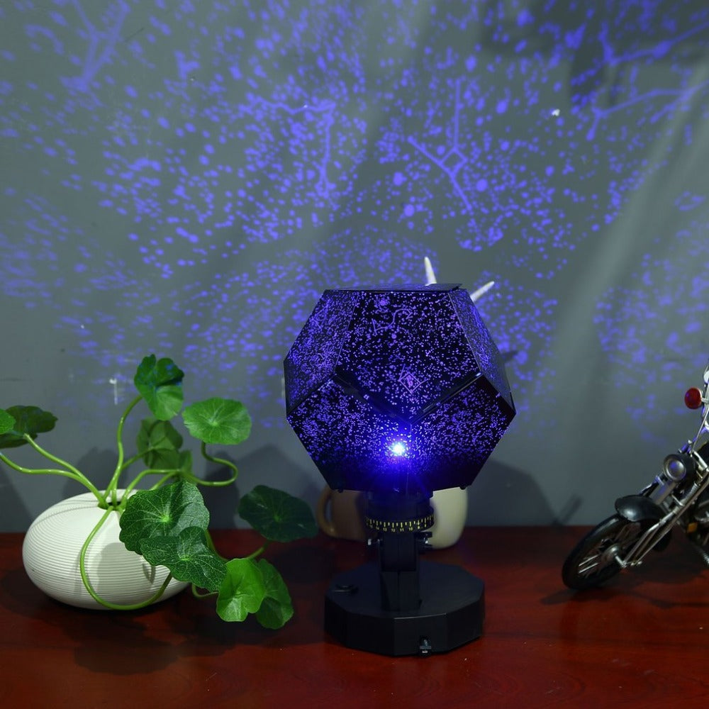 Black dodecahedron projector on a desk casting blue constellation stars across the wall