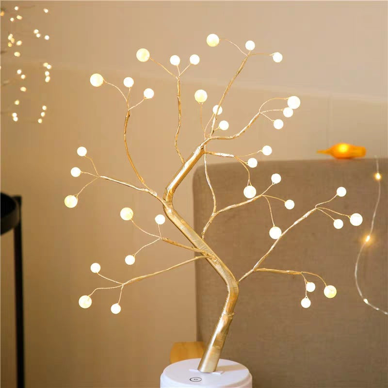 Round bulb tree lamp glowing beside a bed with fairy lights in the background