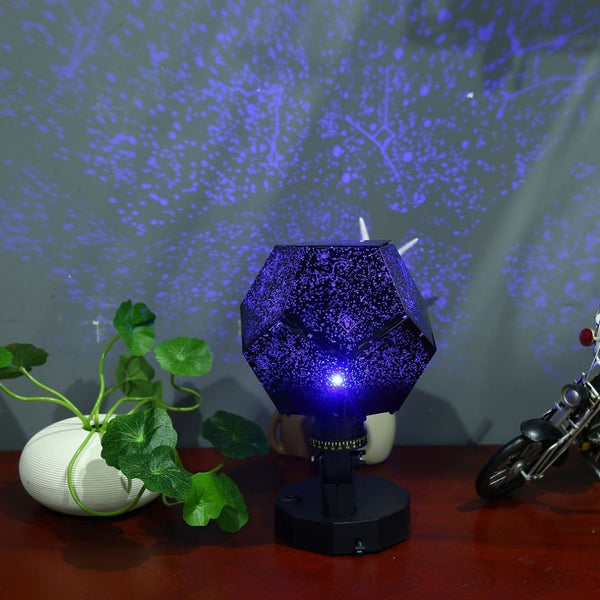 Black dodecahedron projector on a desk casting blue constellation stars across the wall
